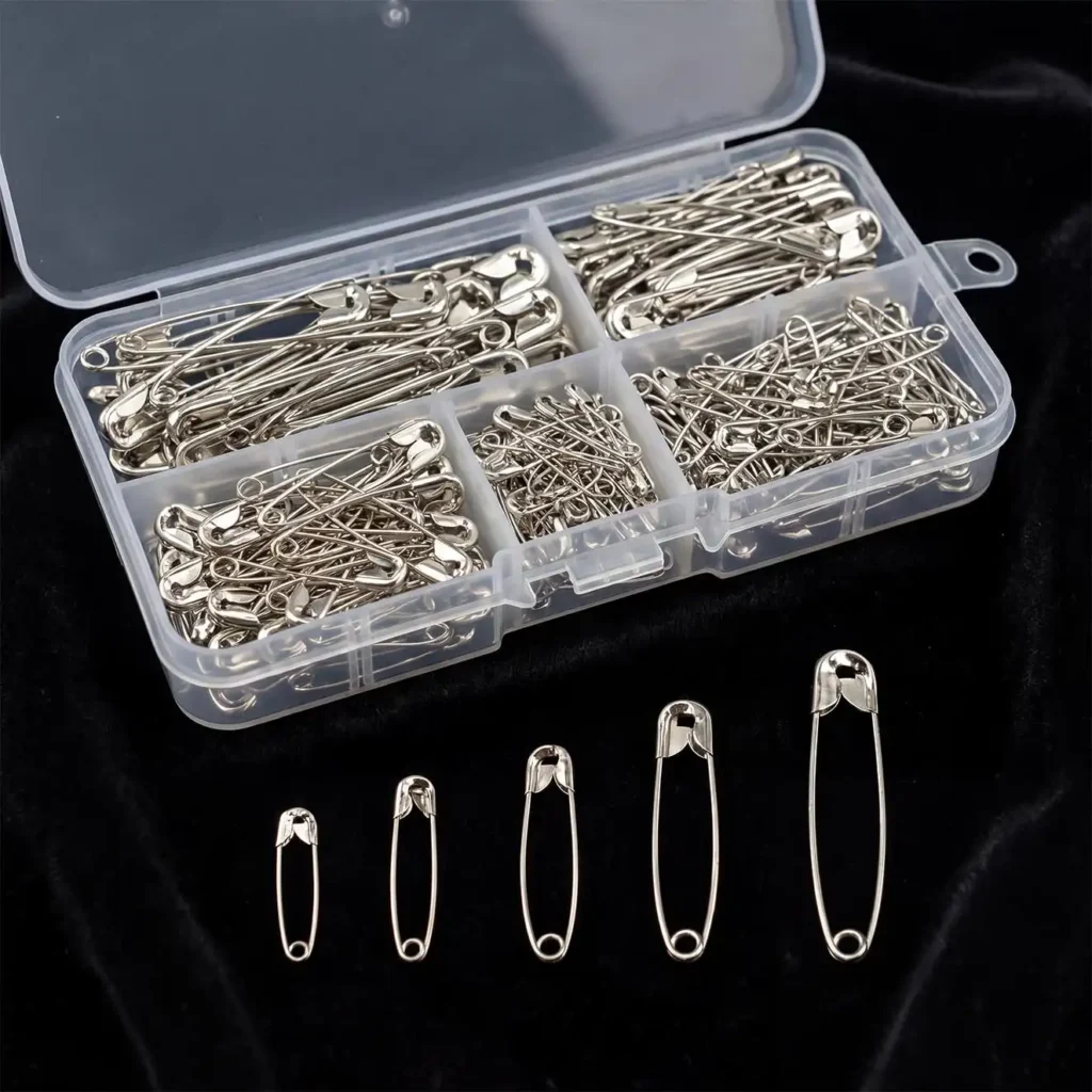 A clear plastic compartmentalized storage box filled with 150 silver hardened steel safety pins in five assorted sizes.