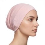 Side profile of a woman wearing a soft, stretchable flesh-pink inner hijab cap against a white background