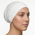 Side profile of a woman wearing a soft, stretchable ghost white inner hijab cap against a white background.