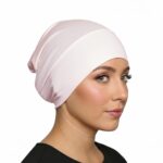 Side profile of a woman wearing a soft, stretchable misty-rose inner hijab cap against a white background