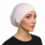 Side profile of a woman wearing a soft, stretchable misty-rose inner hijab cap against a white background