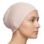 Side profile of a woman wearing a soft, stretchable peach-puff inner hijab cap against a white background
