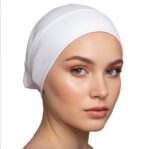 Side profile of a woman wearing a soft, stretchable white inner hijab cap against a white background.
