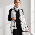 Woman draped in an ivory-white scarf with black polka dots and a thick black frame border.