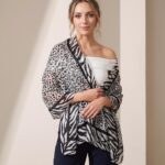 Woman wearing a black and white leopard and zebra print oversized shawl over a black outfit.